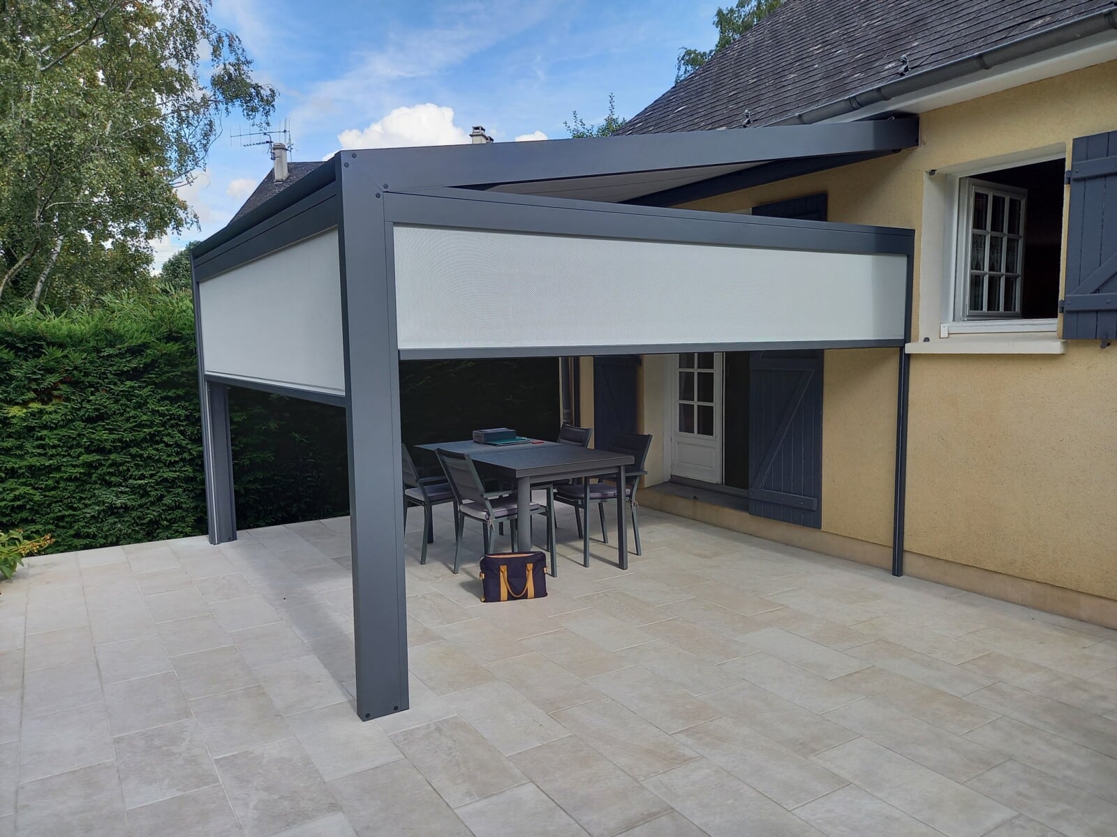 Pergola COCOON de la gamme VERANCO avec store de toiture en toile et store en façade.